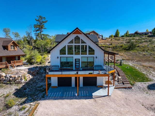 1610 N Mackinaw Way, Garden City, UT 84028 - back of house with driveway, an attached garage, board and batten siding, and stairway