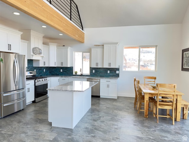 1610 N Mackinaw Way, Garden City, UT 84028 - kitchen with white cabinets, light stone countertops, appliances with stainless steel finishes, and a kitchen island