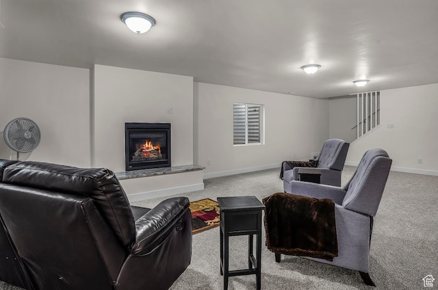 living area featuring light carpet, a warm lit fireplace, and baseboards