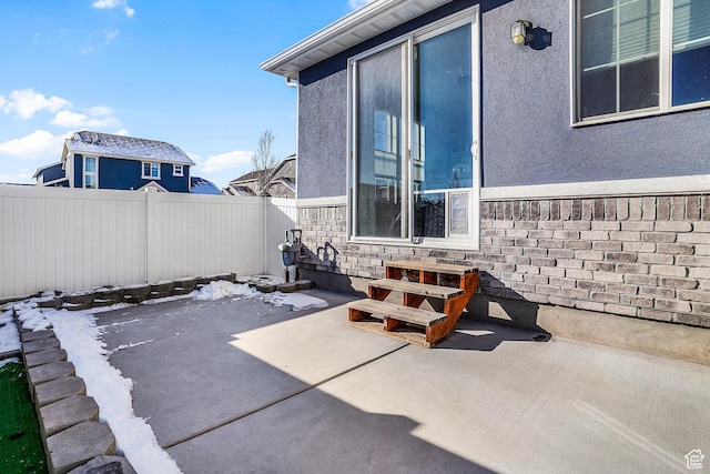 snow covered patio with a fenced backyard