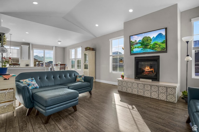 living room with dark wood-style flooring, recessed lighting, a glass covered fireplace, vaulted ceiling, and baseboards