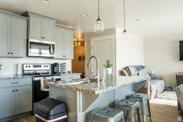 987 W 40 N, Spanish Fork, UT 84660 - kitchen featuring a breakfast bar area, stainless steel appliances, light stone countertops, a center island with sink, and decorative light fixtures