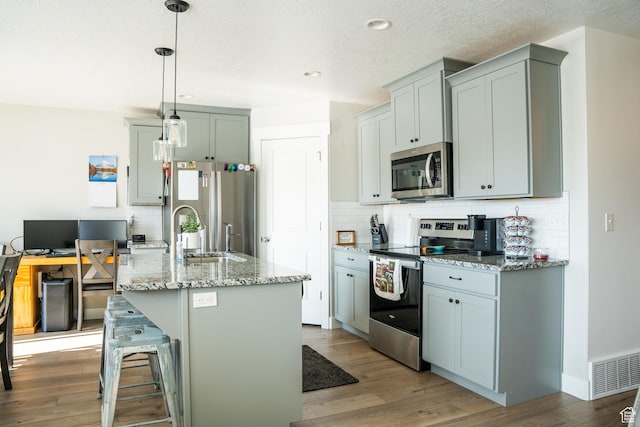 987 W 40 N, Spanish Fork, UT 84660 - kitchen with a breakfast bar, light stone counters, hanging light fixtures, an island with sink, and stainless steel appliances