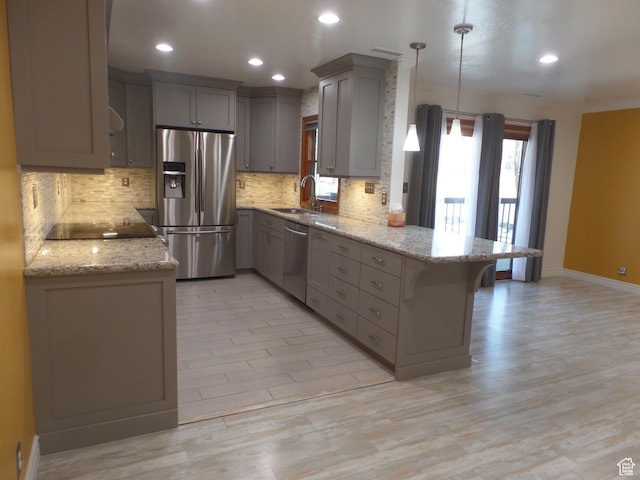 kitchen with sink, a breakfast bar area, kitchen peninsula, pendant lighting, and stainless steel appliances
