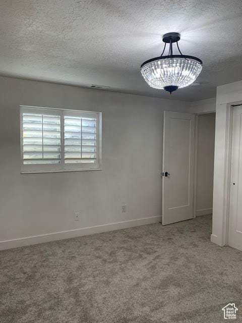 carpeted empty room with a textured ceiling
