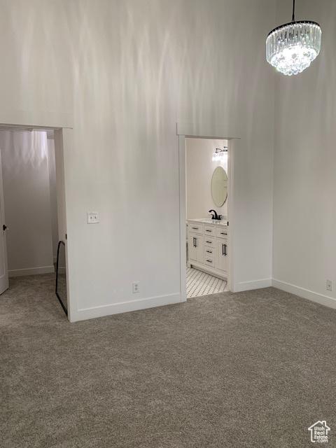 empty room with light colored carpet and an inviting chandelier