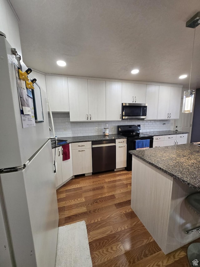 3673 S 2200th St W Unit 13, West Valley City, UT 84119 - kitchen with white cabinetry, stainless steel appliances, dark hardwood / wood-style floors, tasteful backsplash, and decorative light fixtures
