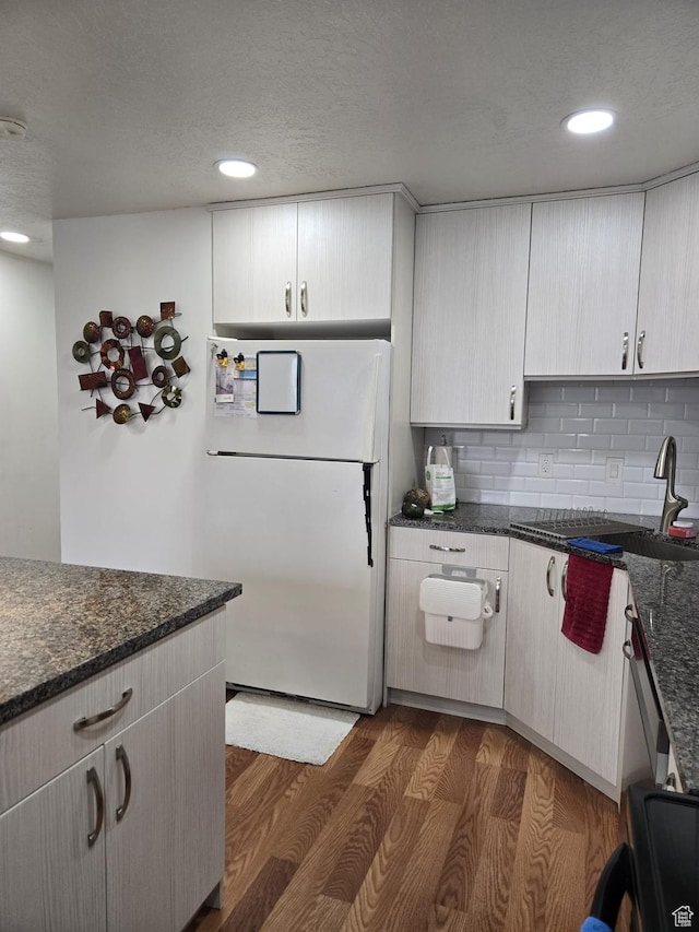 3673 S 2200th St W Unit 13, West Valley City, UT 84119 - kitchen featuring white refrigerator, dark hardwood / wood-style floors, and dark stone countertops