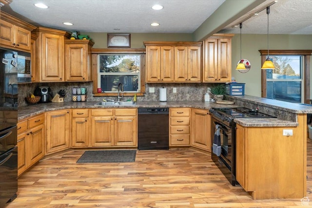 kitchen featuring black appliances, sink, hanging light fixtures, kitchen peninsula, and light hardwood / wood-style flooring