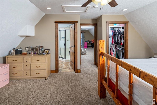 carpeted bedroom featuring ceiling fan, a closet, vaulted ceiling, and a textured ceiling