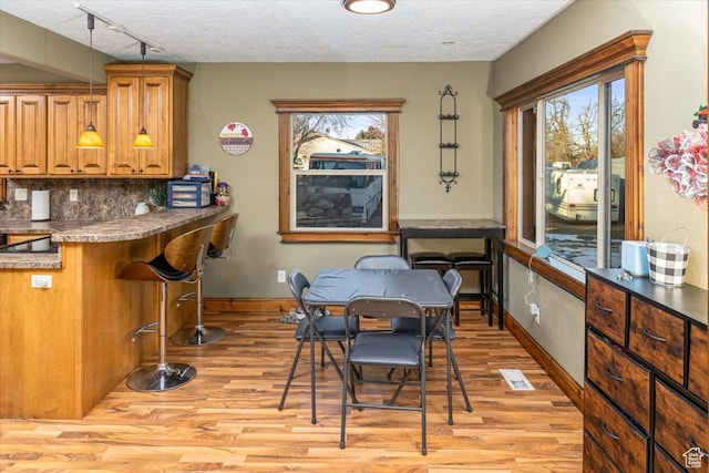 dining room featuring track lighting, light hardwood / wood-style floors, and a textured ceiling