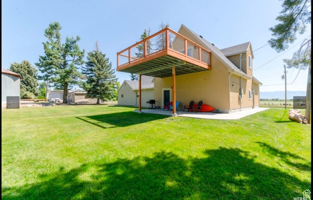 rear view of property with a patio, a wooden deck, and a lawn
