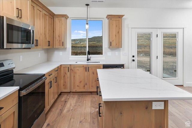 kitchen with sink, light hardwood / wood-style flooring, appliances with stainless steel finishes, tasteful backsplash, and decorative light fixtures