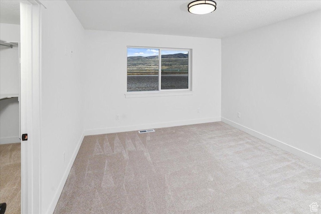 carpeted empty room featuring a textured ceiling