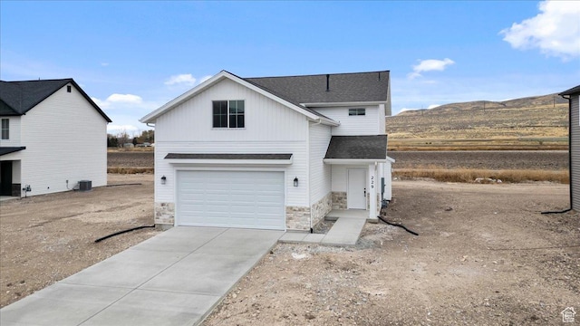 view of front facade with a garage, a mountain view, and central air condition unit