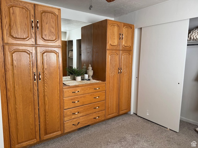 interior space featuring ceiling fan, light colored carpet, and a textured ceiling