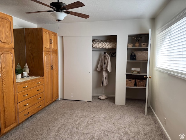 unfurnished bedroom with ceiling fan, two closets, light colored carpet, and a textured ceiling