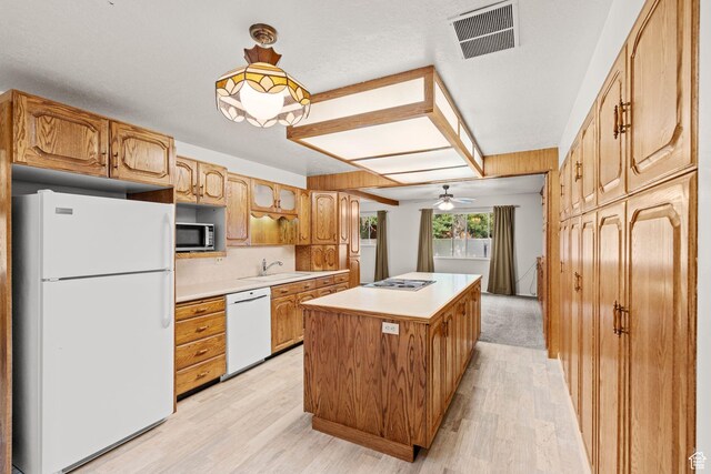 kitchen featuring sink, light hardwood / wood-style flooring, appliances with stainless steel finishes, hanging light fixtures, and a kitchen island