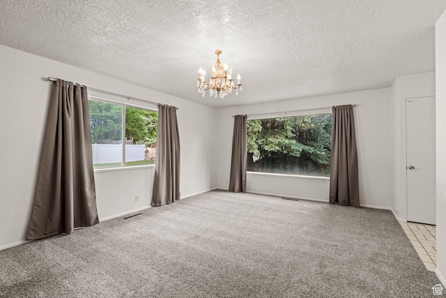 carpeted spare room with a textured ceiling and a chandelier