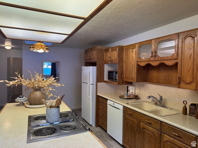 kitchen with sink, a textured ceiling, hardwood / wood-style flooring, white appliances, and backsplash