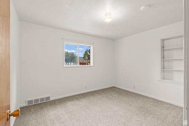 carpeted spare room with a textured ceiling