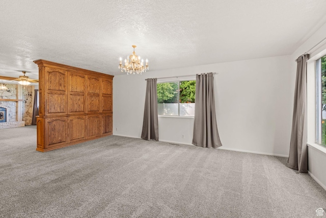 carpeted spare room featuring a wealth of natural light, a notable chandelier, and a textured ceiling