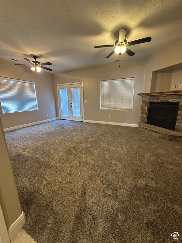 1288 N Cedar Blvd Unit 38-F, Cedar City, UT 84721 - unfurnished living room featuring ceiling fan, a stone fireplace, carpet floors, and a textured ceiling