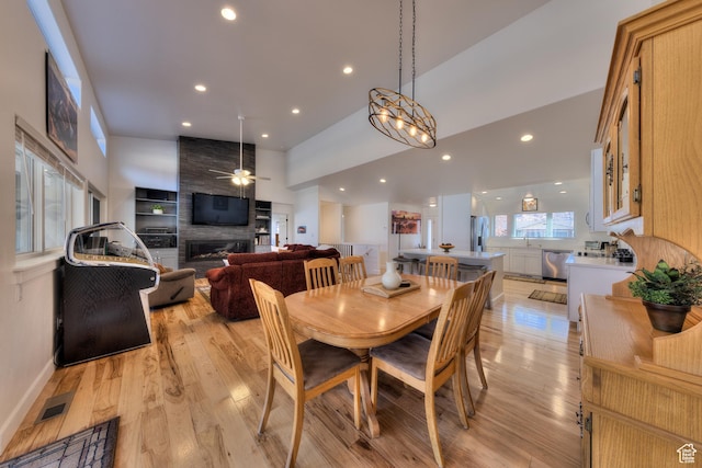 4230 S Beeman Rd, Moab, UT 84532 - dining space featuring a fireplace, sink, light hardwood / wood-style flooring, and a high ceiling