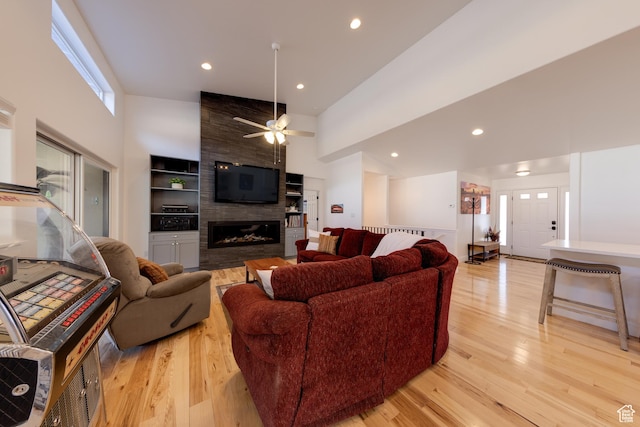4230 S Beeman Rd, Moab, UT 84532 - living room featuring ceiling fan, a large fireplace, light hardwood / wood-style floors, and a towering ceiling