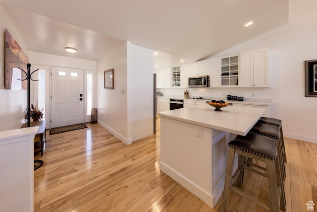 4230 S Beeman Rd, Moab, UT 84532 - kitchen with lofted ceiling, a breakfast bar, light hardwood / wood-style flooring, appliances with stainless steel finishes, and white cabinets