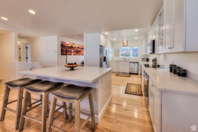 4230 S Beeman Rd, Moab, UT 84532 - kitchen with sink, appliances with stainless steel finishes, white cabinetry, a kitchen breakfast bar, and light wood-type flooring