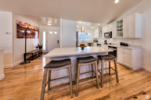 4230 S Beeman Rd, Moab, UT 84532 - kitchen with a breakfast bar area, a center island, light hardwood / wood-style flooring, appliances with stainless steel finishes, and white cabinets