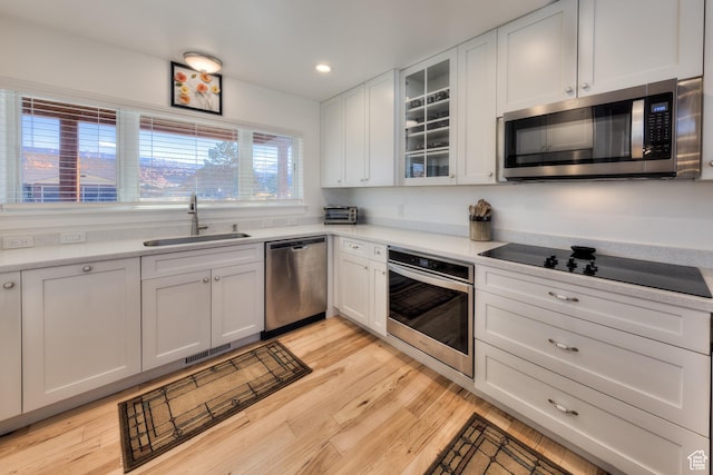4230 S Beeman Rd, Moab, UT 84532 - kitchen featuring stainless steel appliances, white cabinetry, sink, and light hardwood / wood-style floors