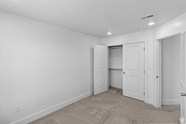 unfurnished bedroom featuring a closet and light carpet