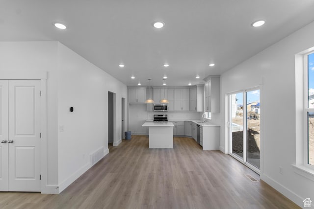kitchen featuring sink, decorative light fixtures, light hardwood / wood-style flooring, a kitchen island, and stainless steel appliances