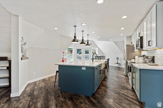 3388 N Eden Hills Dr, Eden, UT 84310 - kitchen with appliances with stainless steel finishes, white cabinetry, an island with sink, blue cabinets, and decorative light fixtures