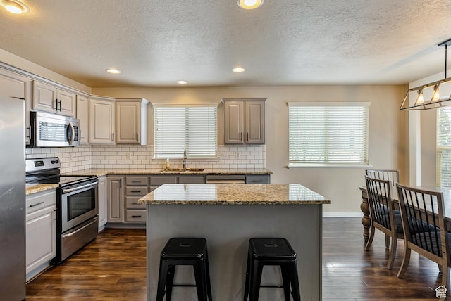 693 N Devonshire Dr, Saratoga Springs, UT 84045 - kitchen featuring sink, decorative light fixtures, a center island, stainless steel appliances, and light stone countertops