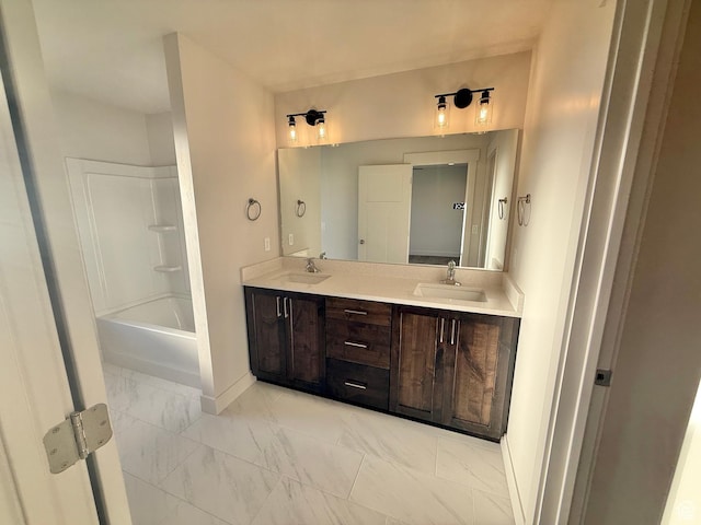 bathroom with double vanity, baseboards, marble finish floor, and a sink