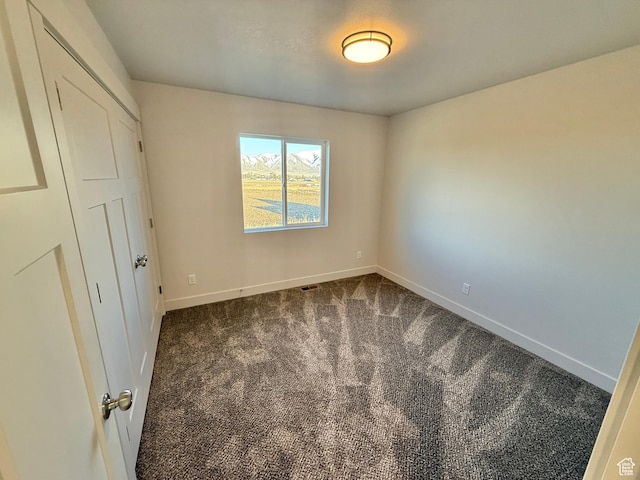 unfurnished bedroom featuring visible vents, baseboards, and dark carpet
