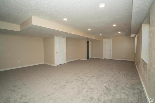 basement featuring light colored carpet and a textured ceiling