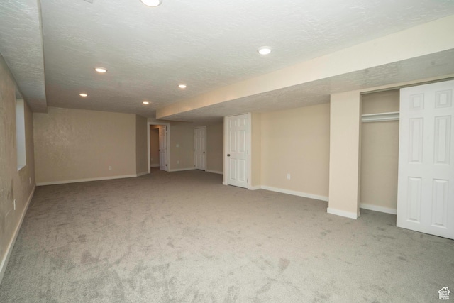 basement featuring light carpet and a textured ceiling