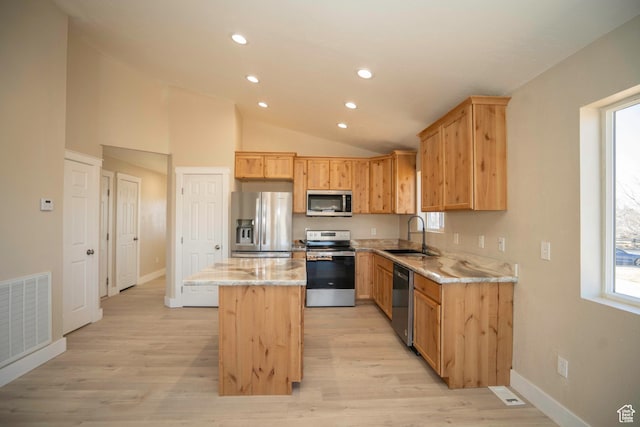 kitchen featuring sink, a center island, vaulted ceiling, appliances with stainless steel finishes, and light stone countertops