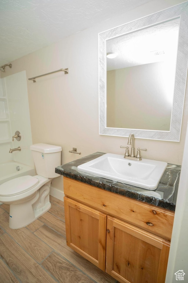 full bathroom with hardwood / wood-style flooring, vanity, shower / bathing tub combination, and toilet