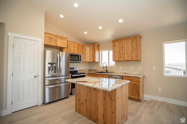 kitchen featuring lofted ceiling, sink, a center island, light stone counters, and stainless steel appliances