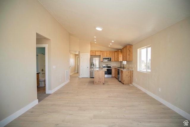 kitchen with sink, stainless steel appliances, a kitchen island, vaulted ceiling, and light wood-type flooring