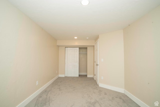 unfurnished bedroom featuring light colored carpet and a closet
