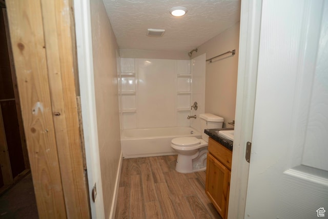 full bathroom featuring wood-type flooring, vanity, toilet, tub / shower combination, and a textured ceiling