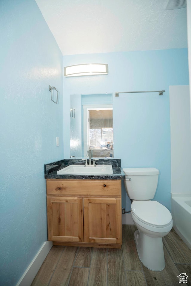bathroom with hardwood / wood-style flooring, vanity, a bathtub, and toilet