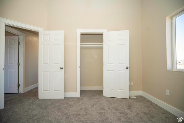 unfurnished bedroom featuring dark carpet and a closet