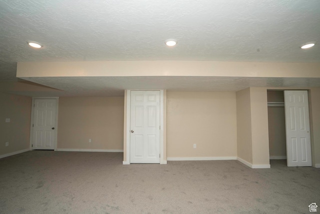 basement featuring light carpet and a textured ceiling